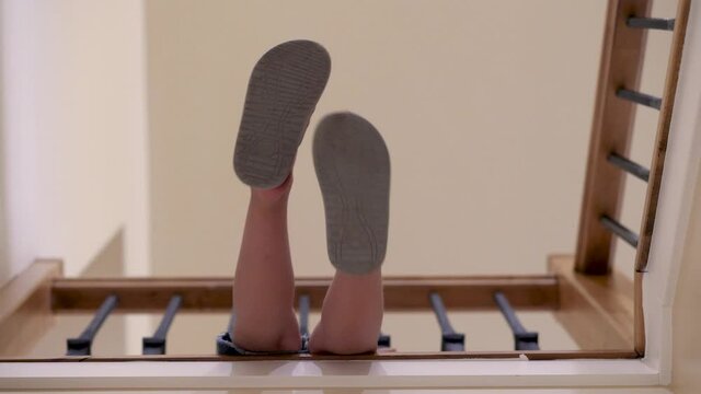 feet with sandals dangling over stairs. this video shows kid&rsquo;s feet dangling over the wooden stairs.