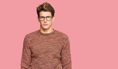 Handsome caucasian man wearing casual sweater and glasses with serious expression on face. simple and natural looking at the camera.