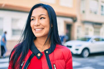 Young latin woman smiling happy walking at the city.