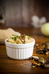 cooked rice with dried forest mushrooms on a wooden table