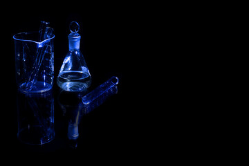 Different laboratory glassware with water and empty with reflection isolated on black