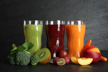 Delicious colorful juices in glasses and fresh ingredients on black table