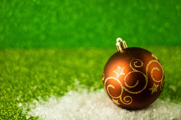 Perfect and simple Christmas concept: decorative Christmas ball with golden glitter, green glitter background, selective focus, free copy space