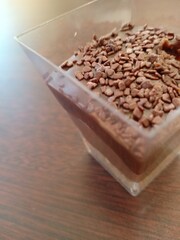 Close up of chocolate beans on the top of a chocolate mousse in a tranparent glass 