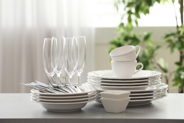 Set of clean dishware, cutlery and champagne glasses on table indoors