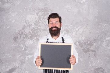 Caucasian hipster male cook with happy face holding empty blackboard advertising culinary school master class, cuisine