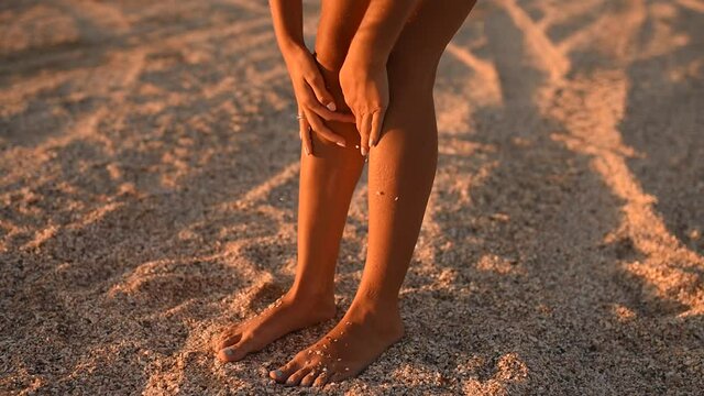 young woman clean tanned legs. skinny tanned female legs covered with seashells and sea stones on the tropical ocean shore. slow motion. High quality FullHD footage. 