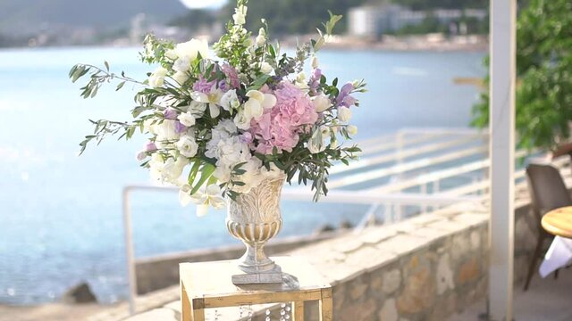 graceful vase with a bouquet of peonies, lisianthus, delphiniums and olive twigs, wedding venue decor