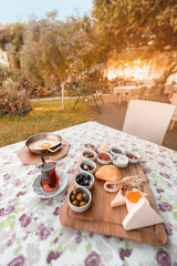 Freshly prepared Turkish Breakfast consisting of scrambled eggs, tea, vegetable salad and an assortment of snacks and pickles. Beautifully set table in the outdoor restaurant in the garden