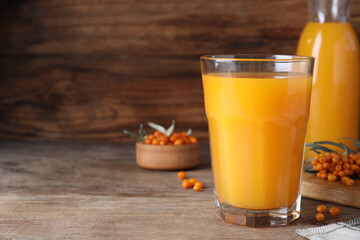 Delicious sea buckthorn juice on wooden table, closeup. Space for text