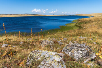 deux pierres au bord d'un lac bleu profond bordé de prairies