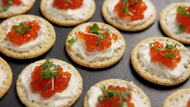 Salmon caviar and soft cheese savory crackers, party food. rotating video