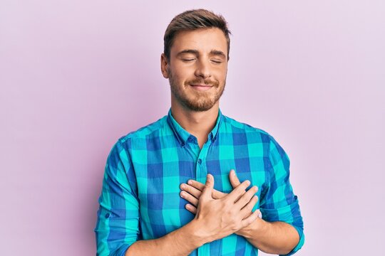 Handsome caucasian man wearing casual clothes smiling with hands on chest with closed eyes and grateful gesture on face. health concept.