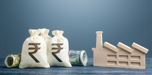 Indian rupee money bags and industrial factory plant. Investments in production and energy...