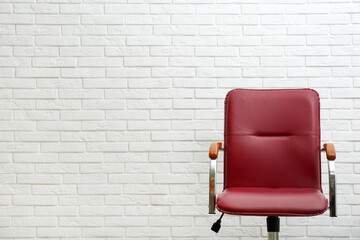 Comfortable office chair near white brick wall. Space for text