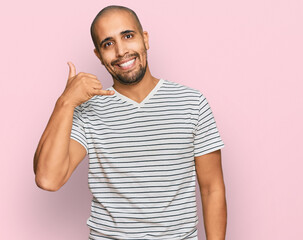 Fototapeta premium Hispanic adult man wearing casual clothes smiling doing phone gesture with hand and fingers like talking on the telephone. communicating concepts.