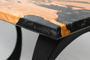 Close up of the corner of a wood and epoxy table on a white backdrop