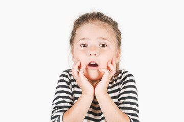 Frightened girl with hands touching her cheeks. Shocking girl looking at camera with open mouth. Posing little girl wearing striped shirt. Presentation, advertisement concept.