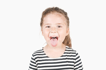 Funny girl showing tongue. Teasing, playing girl looking at camera with smiling eyes. Posing little girl wearing striped shirt.