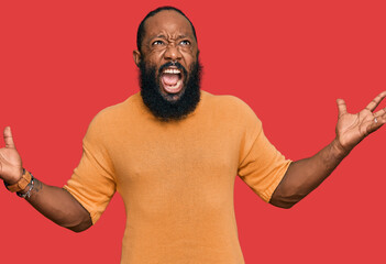 Young african american man wearing casual clothes crazy and mad shouting and yelling with aggressive expression and arms raised. frustration concept.