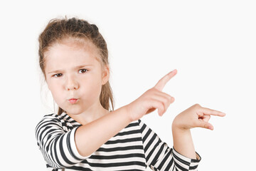 Upset girl pointing her fingers to side, away and keeping silence. Posing little girl wearing striped shirt, looking at camera on isolated background. Secret recommendation, betrayal concept.