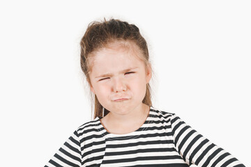Close up portrait of girl suspiciously looking at camera with head tilted to one side. Girl trying to understand what's the matter. Posing little girl wearing striped shirt. Isolated background.