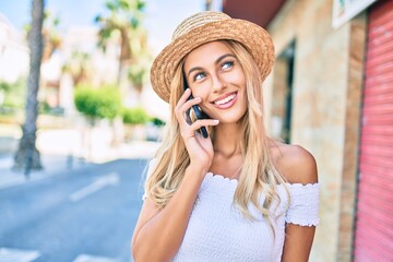 Young blonde tourist girl smiling happy talking on the smartphone at the city.