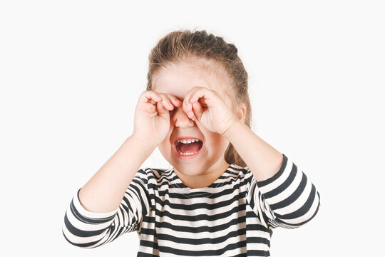 Loudly Crying Girl With Hands Covering Her Eyes. The Upset Girl Is Wiping Tears With Two Hands. Posing Little Girl Wearing A Striped Shirt. Negative Emotion, Depression, Stress Concept.