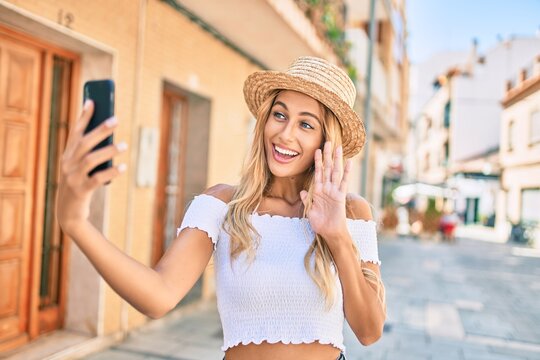 Young blonde tourist girl smiling happy doing video call using smartphone at the city.