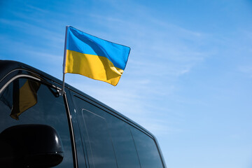 National flag of Ukraine on car window outdoors. Space for text