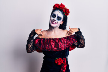 Young woman wearing mexican day of the dead makeup looking confident with smile on face, pointing oneself with fingers proud and happy.