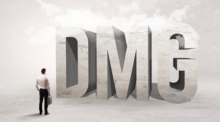 Rear view of a businessman standing in front of DMG abbreviation, attention making concept