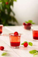 Raspberry alcoholic shots, shot glasses with colored liquor on a white background