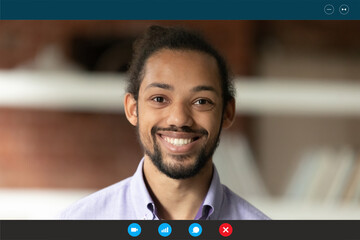 Close up sincere smiling young african american employee looking at web camera, enjoying working...