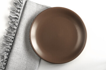 Brown vintage empty plate with tissue napkin on gray background. Top view