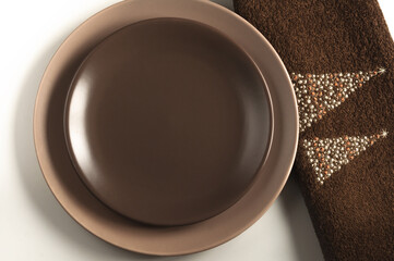 Two brown ceramic plates and a Christmas cloth napkin on a gray background. Top view