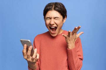 Studio shot of furious annoyed young woman with nose ring opening mouth widely, screaming, being...