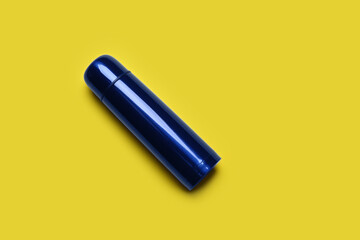 Blue metal thermos on yellow background, top view. Space for text