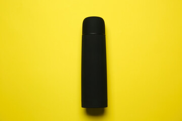 Black thermos on yellow background, top view