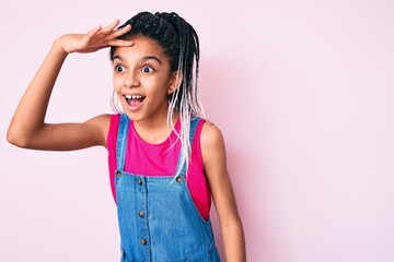 Young african american girl child with braids wearing casual clothes over pink background very happy and smiling looking far away with hand over head. searching concept.