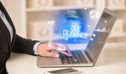 Side view of a business person working on laptop with DUE DILIGENCE inscription, modern business concept
