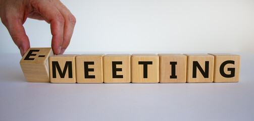 Time to e-meeting. Hand turns a cube and changes the words 'meeting' to 'e-meeting'. Beautiful white background. Business and covid-19 pandemic concept. Copy space.