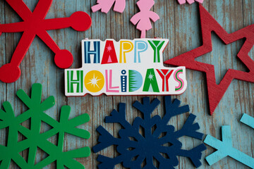 Happy Holidays with rainbow colored snowflakes, on a teal wood background. Useful for Christmas projects