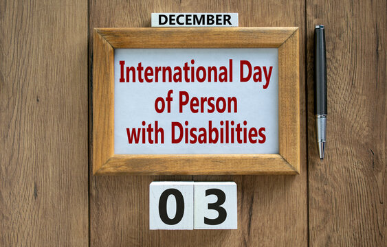 Wooden frame with the inscription 'International Day of Person with Disabilities', blocks with the date december 03. Metallic pen. Beautiful wooden background, copy space. Concept.