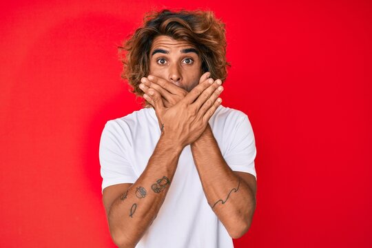 Young hispanic man wearing casual white tshirt shocked covering mouth with hands for mistake. secret concept.