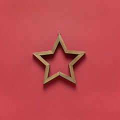 Christmas toy wooden hollow star on dark red background. Festive, New Year concept. Square format, flat lay. Minimal style. Top view