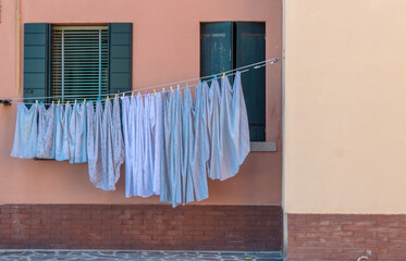 linge en train de sécher sur une corde attachée devant une fenêtre en Italie