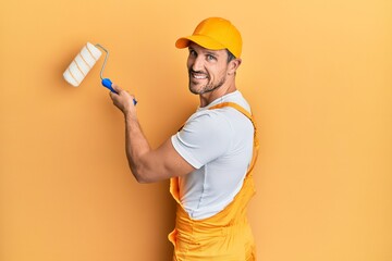 Young caucasian painter smiling happy painting wall using roller. - obrazy, fototapety, plakaty