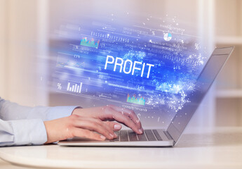 Closeup of businessman hands working on laptop with PROFIT inscription, succesfull business concept
