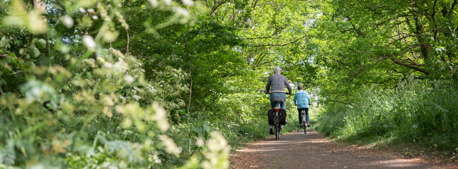 women on bicycle on narrow bike path through spring trees in the centre of holland